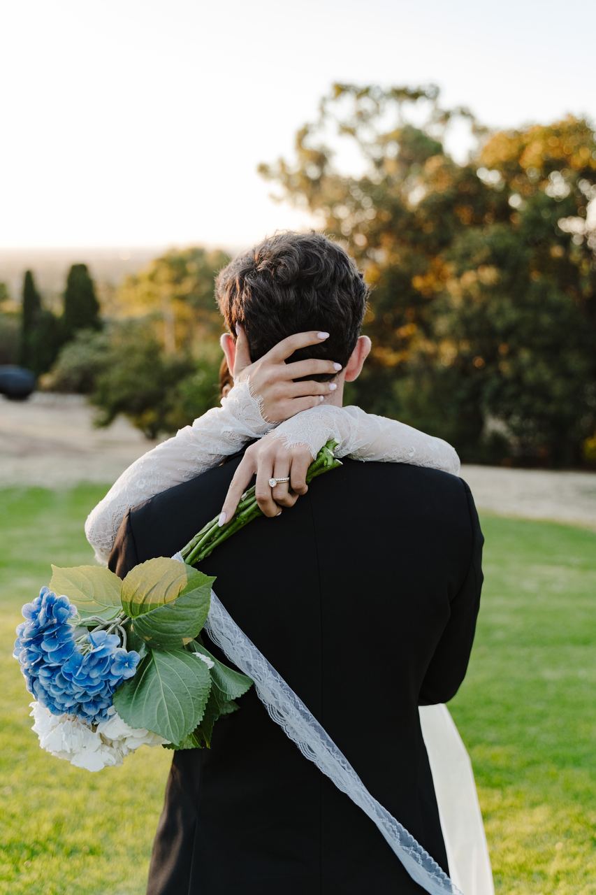 A hug with the bouquet held behind