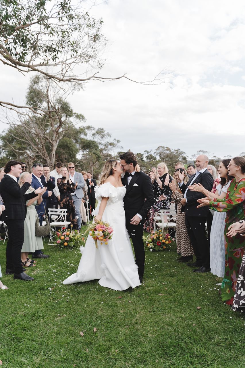 Zak and Zoe kissing in the aisle as the guests cheer