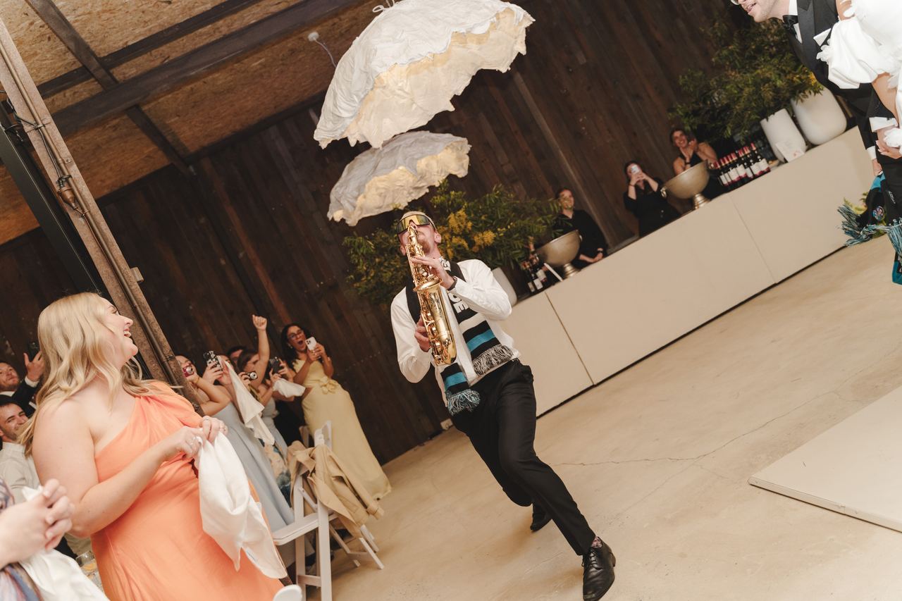 A saxophonist playing the couple into the barn