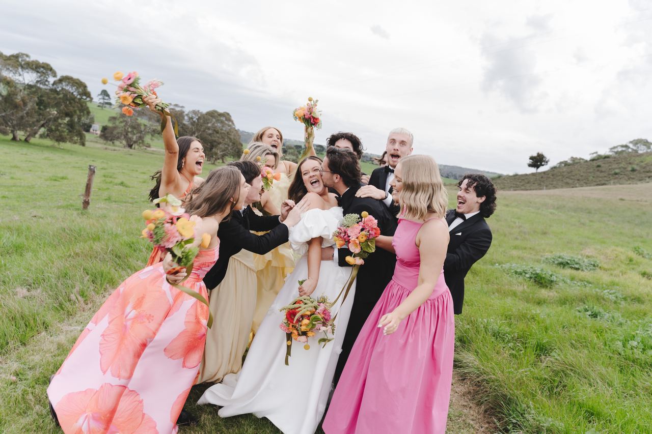 The bridesmaids crowding in for a hug in the long grass