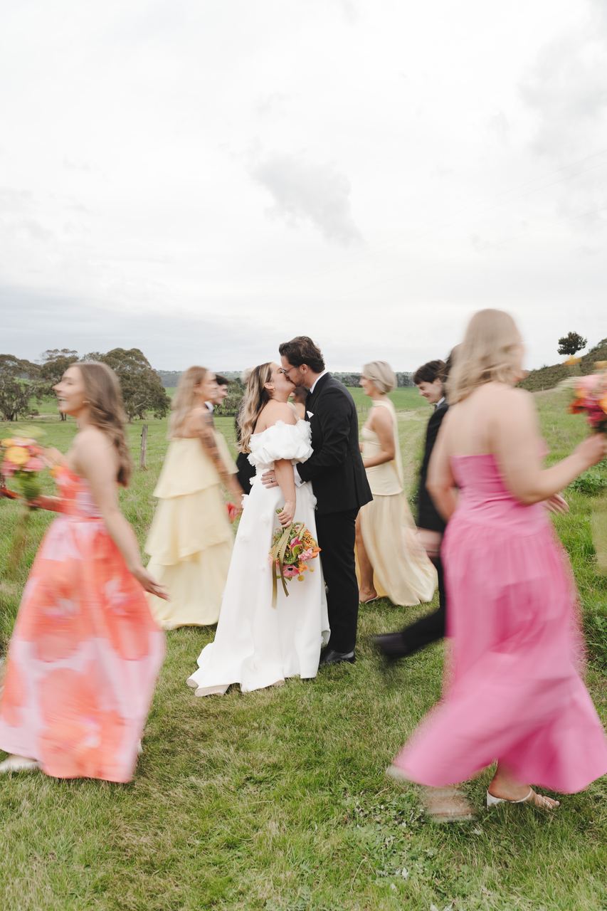Zak and Zoe kissing as the bridesmaids walk past