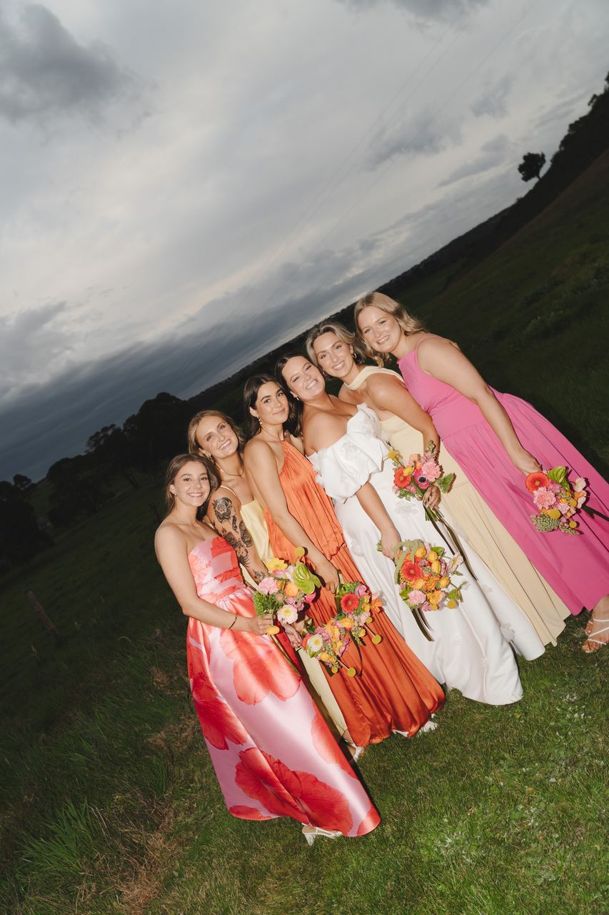 The bridesmaids huddled together under a grey sky