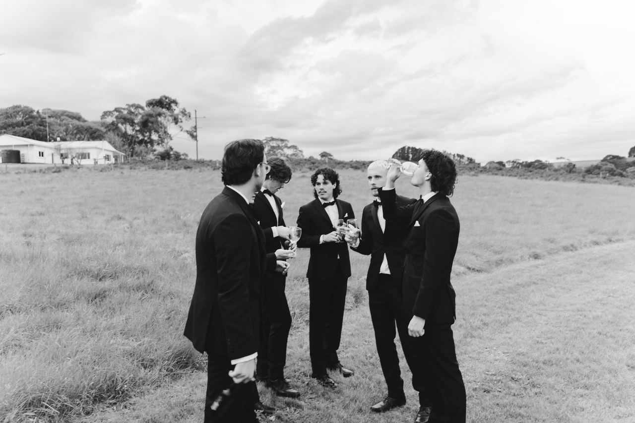 The groomsmen sharing a drink in the paddock