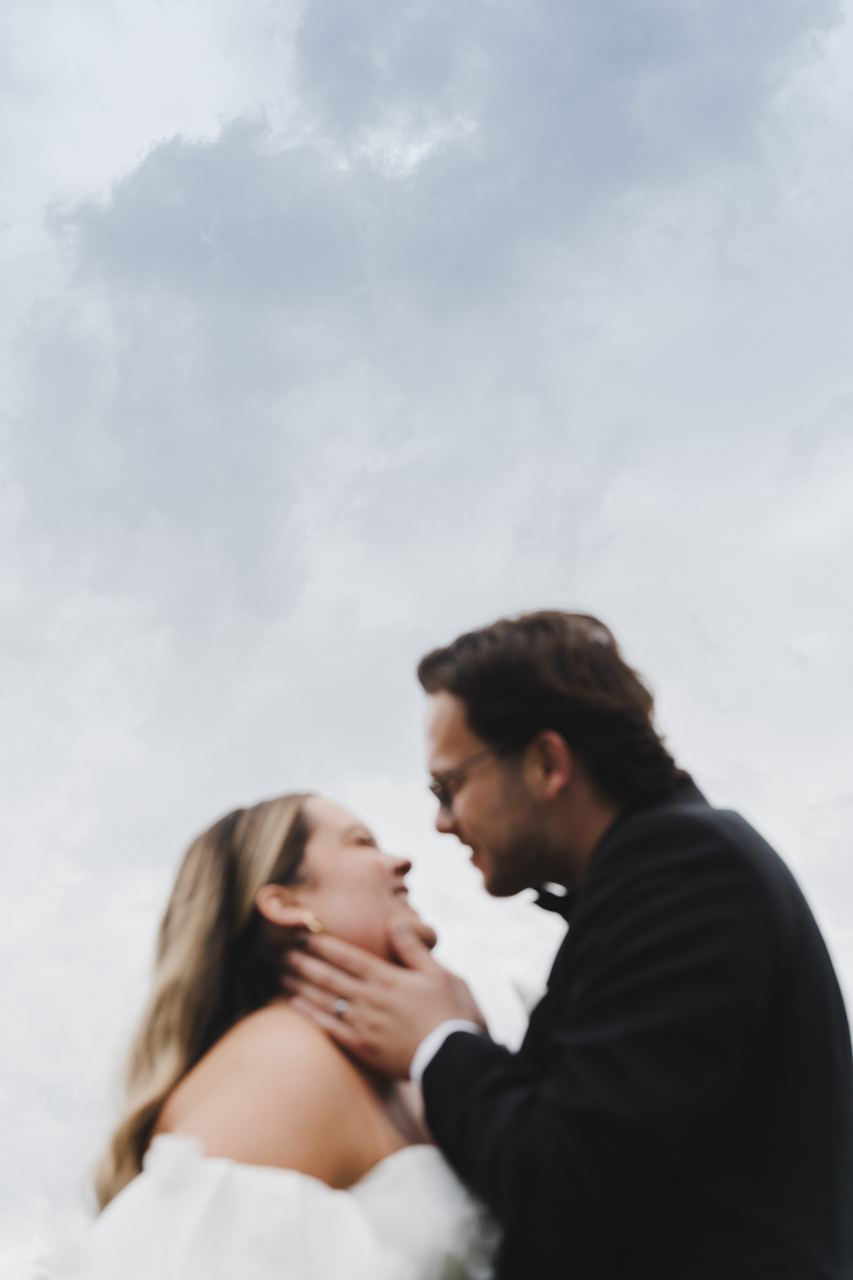 Zak and Zoe about to kiss against the clouds