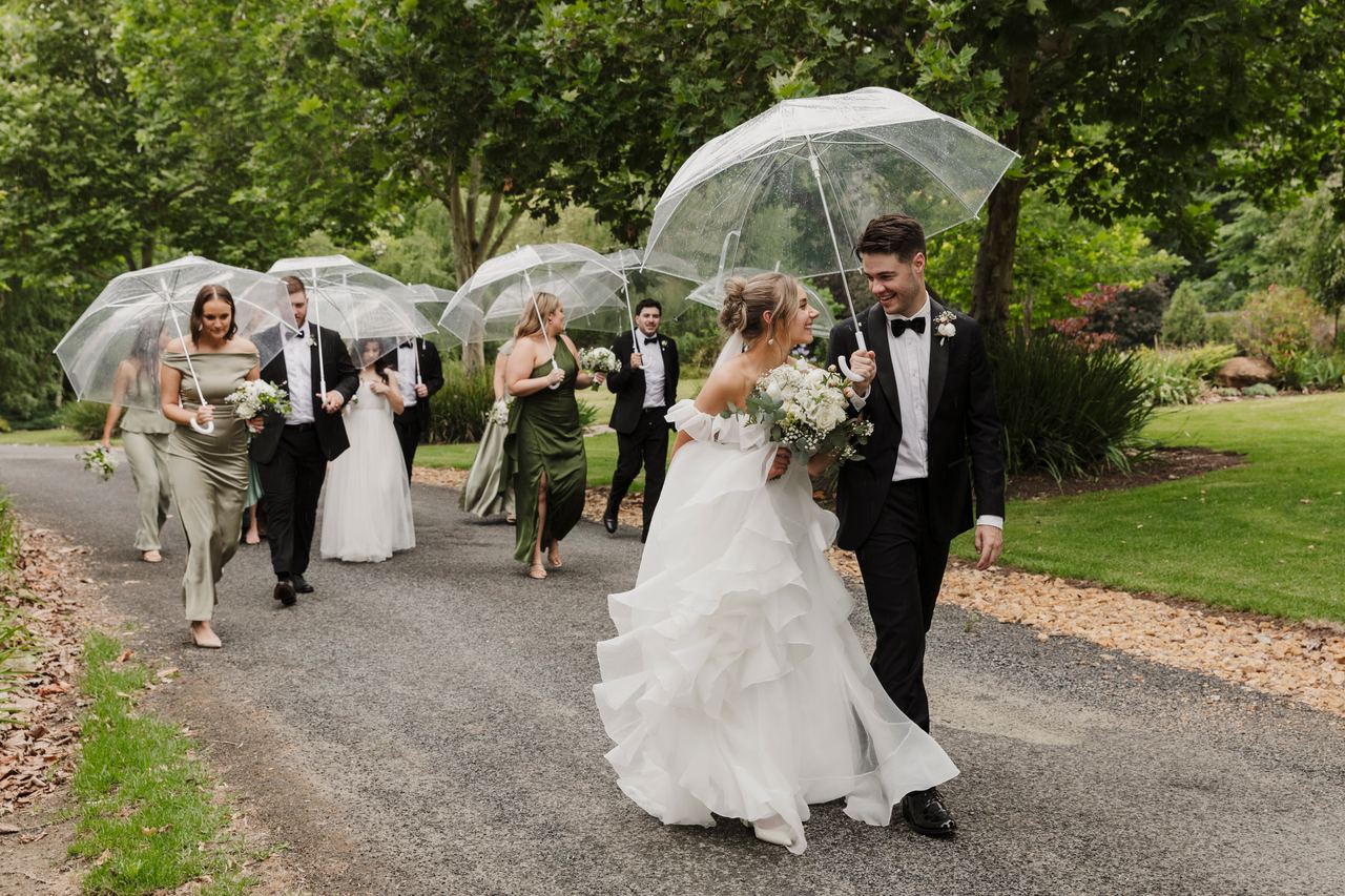 Jason, Lily and the bridal party under clear umbrellas