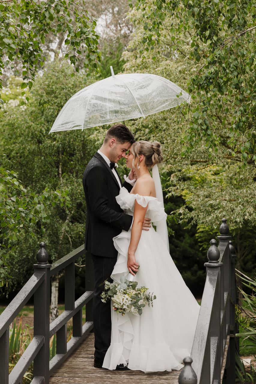 Jason and Lily under an umbrella on a garden bridge