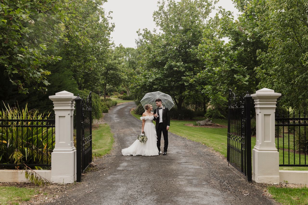 Jason and Lily at the gates under an umbrella