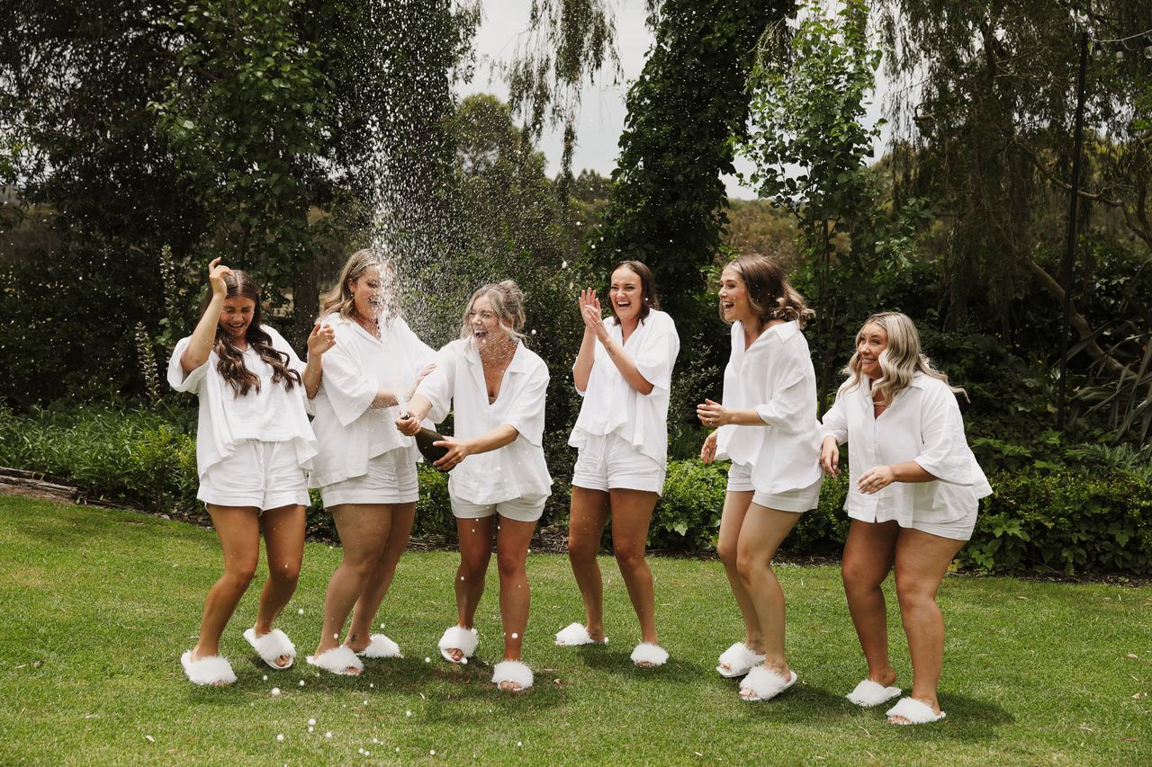 Lily's bridesmaids popping champagne on the lawn