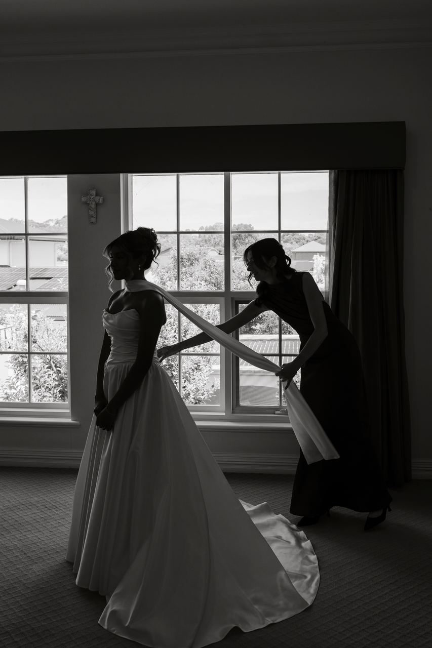 Sinead being buttoned into the dress by the window