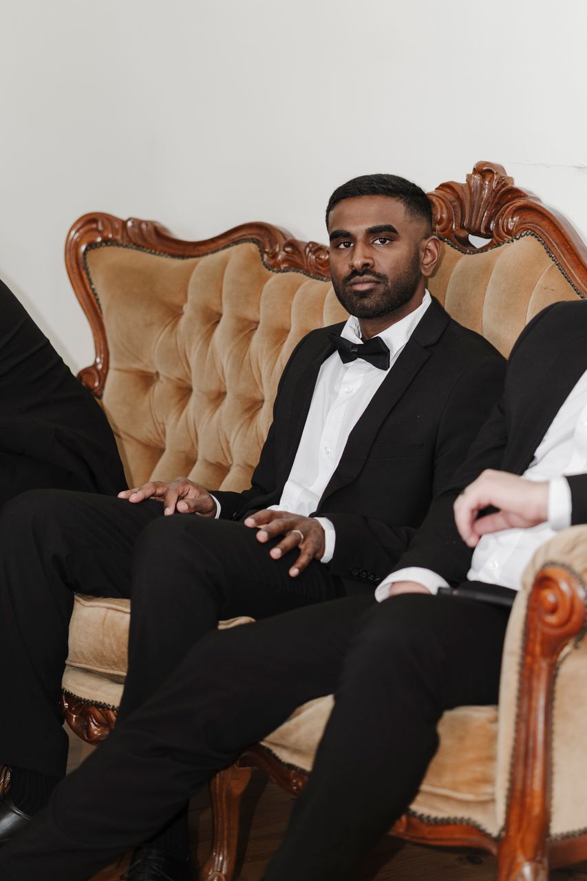 A groomsman relaxing in a tufted chair