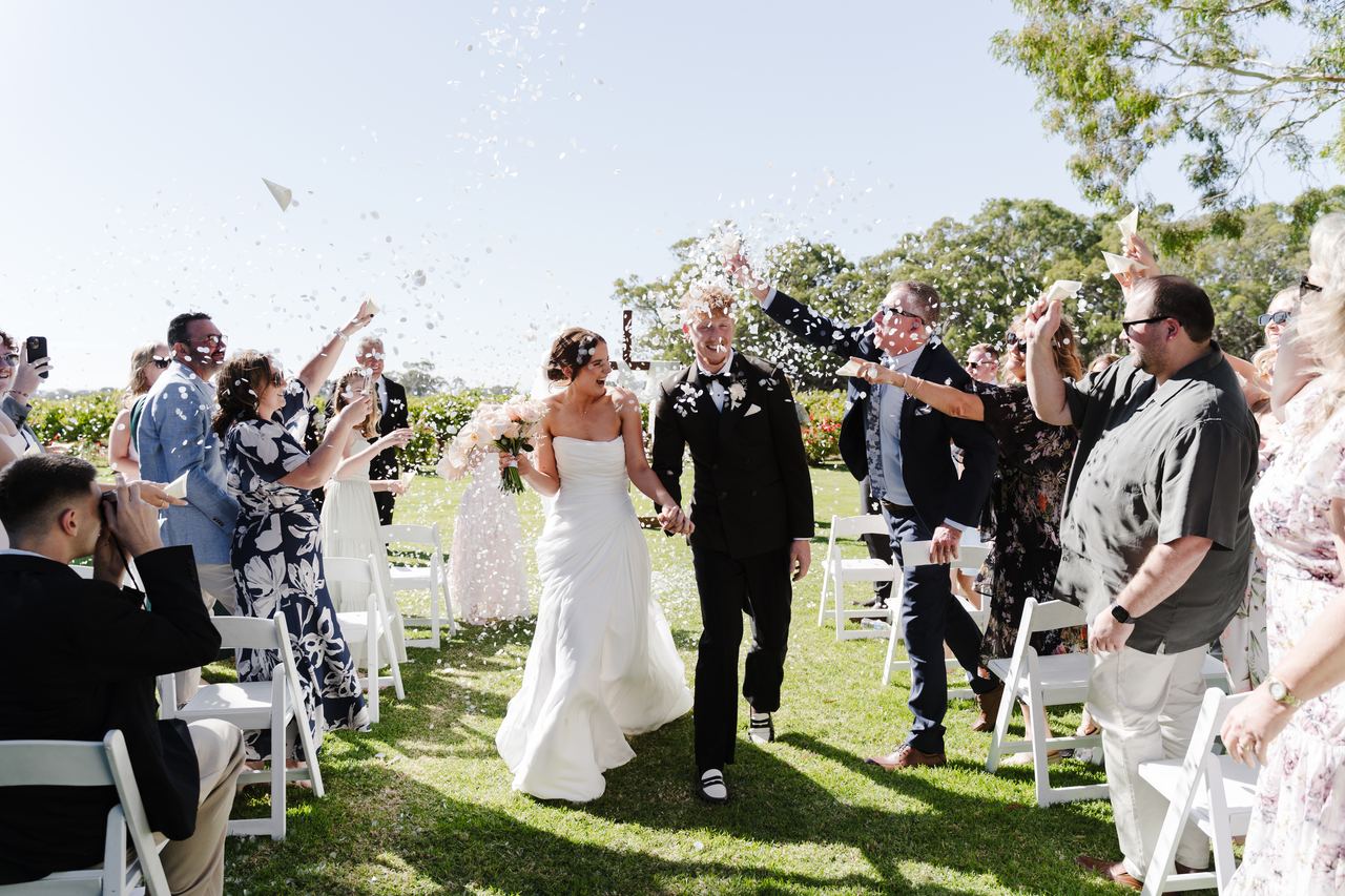 Emma and Liam walking back up the aisle through confetti